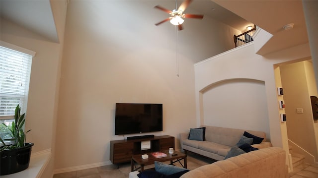 tiled living room with ceiling fan and a high ceiling