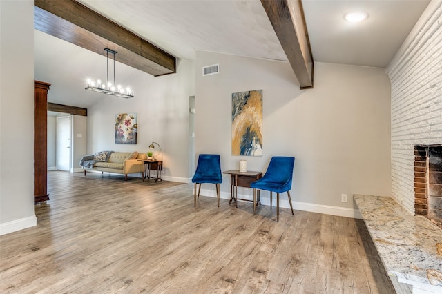 living area with light hardwood / wood-style flooring, an inviting chandelier, high vaulted ceiling, a brick fireplace, and beamed ceiling