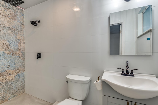 bathroom with vanity, a tile shower, tile walls, and toilet