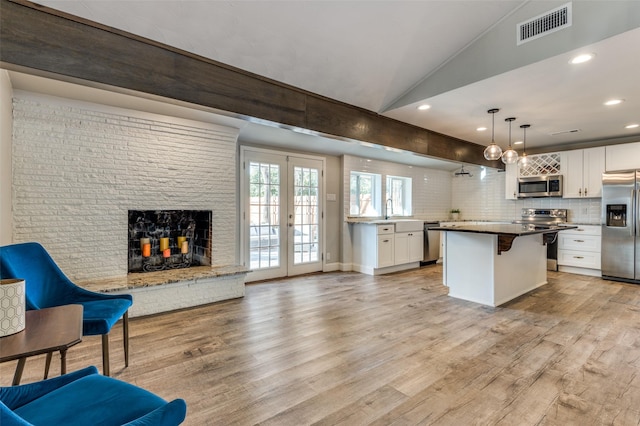 kitchen featuring a kitchen bar, a kitchen island, stainless steel appliances, light hardwood / wood-style floors, and white cabinets