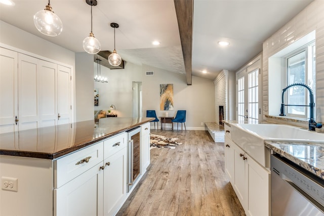 kitchen featuring decorative light fixtures, dishwasher, lofted ceiling, sink, and white cabinets