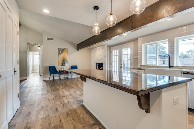 kitchen with sink, decorative light fixtures, white cabinets, and a kitchen island