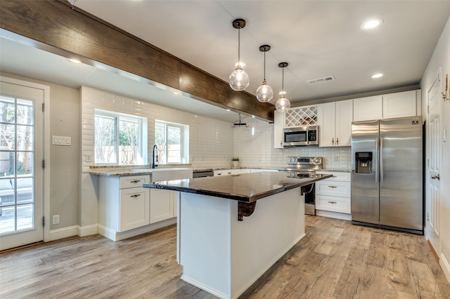 kitchen featuring hanging light fixtures, stainless steel appliances, a center island, and white cabinets