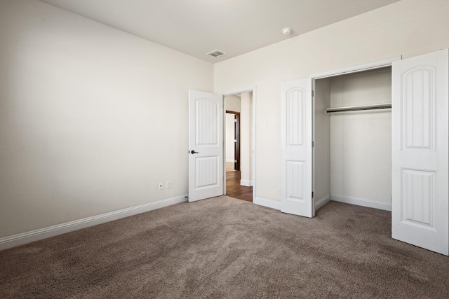 unfurnished bedroom featuring a closet and dark carpet