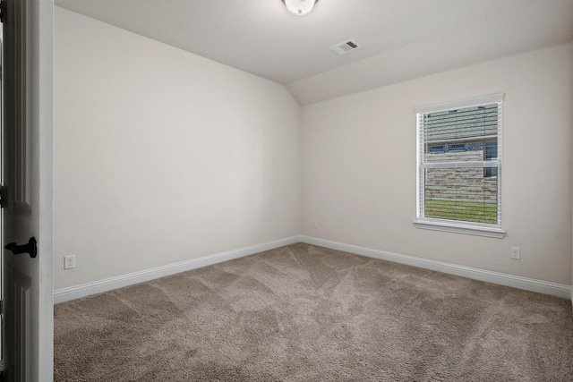 carpeted spare room featuring vaulted ceiling