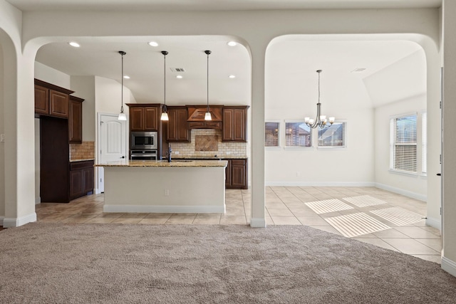 kitchen featuring light stone countertops, backsplash, a kitchen island with sink, and stainless steel appliances