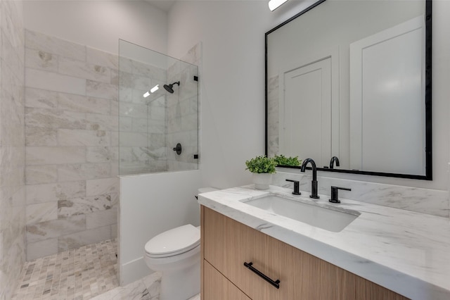 bathroom with toilet, vanity, and a tile shower