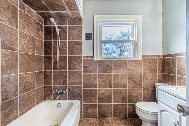 full bathroom with toilet, tile walls, vanity, and tiled shower / bath combo