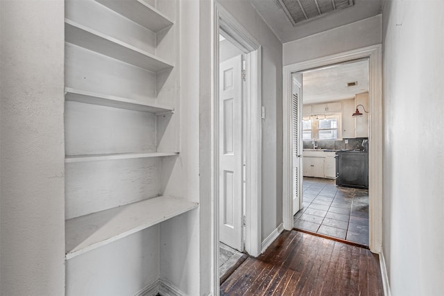 hall featuring built in features, dark hardwood / wood-style floors, and sink