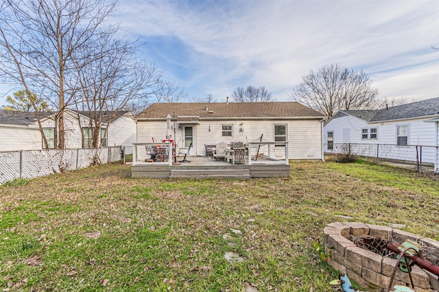 back of house with a deck, a yard, and a fire pit