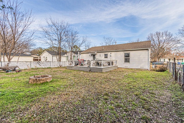 back of house featuring a yard, a wooden deck, and a fire pit