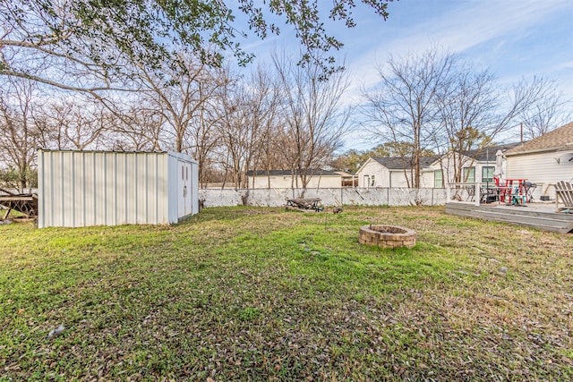 view of yard featuring a storage shed, a wooden deck, and a fire pit