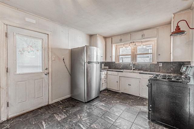 kitchen featuring tasteful backsplash, sink, stainless steel refrigerator, white cabinetry, and black gas stove