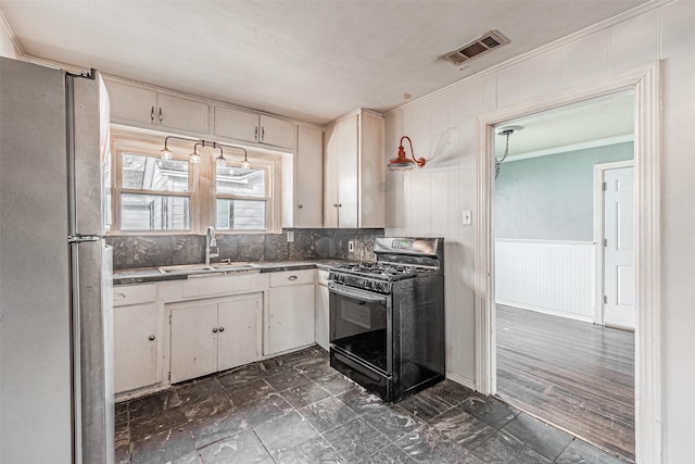 kitchen featuring gas stove, white cabinetry, sink, stainless steel refrigerator, and crown molding