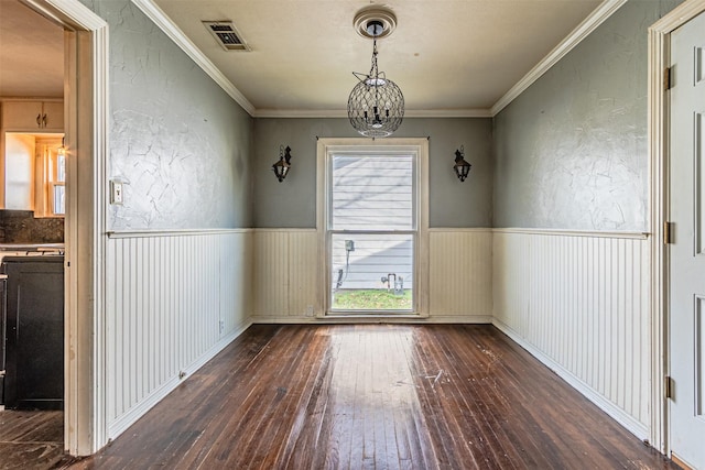 unfurnished dining area featuring dark hardwood / wood-style flooring, ornamental molding, and an inviting chandelier