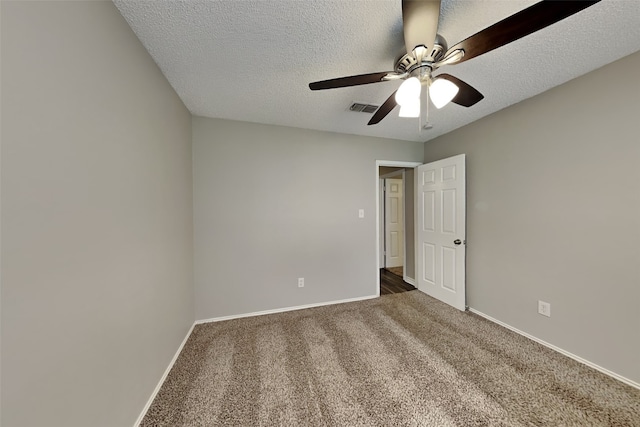 unfurnished room with a textured ceiling, dark colored carpet, and ceiling fan