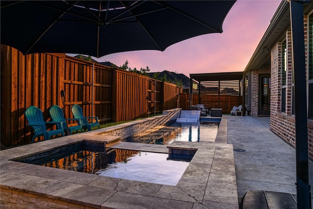 pool at dusk featuring a patio