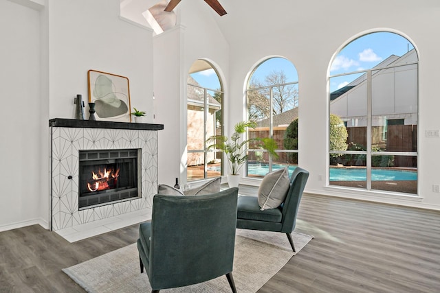 living room featuring ceiling fan, plenty of natural light, wood-type flooring, and a tiled fireplace