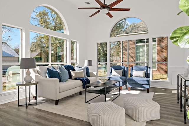 living room featuring a high ceiling, ceiling fan, and wood-type flooring