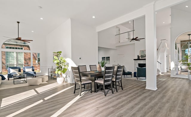 dining space with ceiling fan, a towering ceiling, and hardwood / wood-style flooring