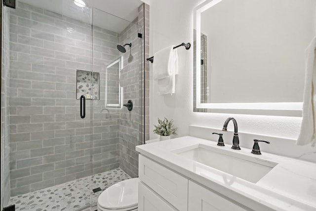 bathroom featuring an enclosed shower, vanity, and toilet