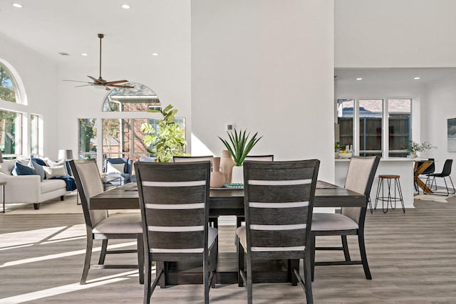 dining space featuring hardwood / wood-style flooring, a high ceiling, ceiling fan, and a healthy amount of sunlight