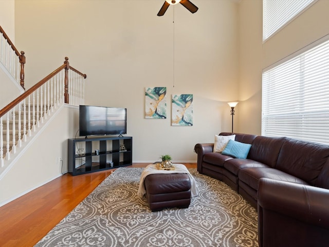 living room with a high ceiling, ceiling fan, and hardwood / wood-style flooring