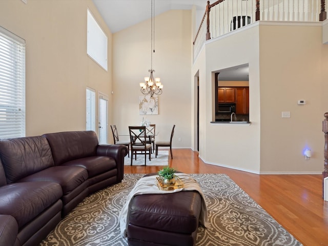 living room with light hardwood / wood-style floors, a high ceiling, and a notable chandelier