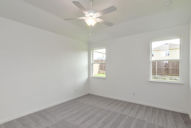 empty room with ceiling fan, light colored carpet, and plenty of natural light