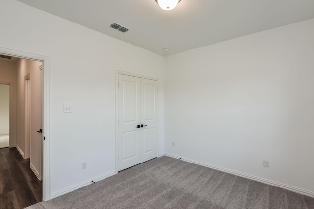 unfurnished bedroom with a closet and dark carpet