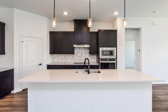 kitchen with sink, backsplash, a center island with sink, and stainless steel appliances