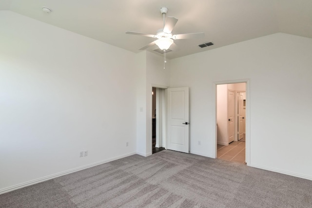 unfurnished bedroom featuring light carpet, ceiling fan, vaulted ceiling, and ensuite bath