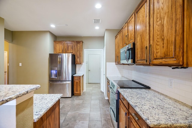 kitchen with backsplash, light stone counters, and stainless steel appliances