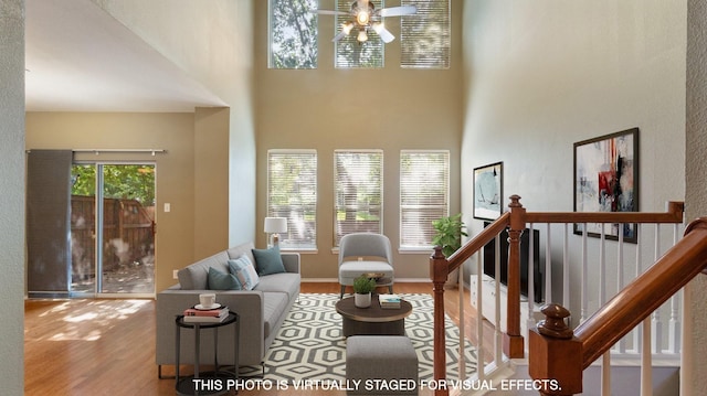 living room with ceiling fan, a towering ceiling, a wealth of natural light, and light hardwood / wood-style floors