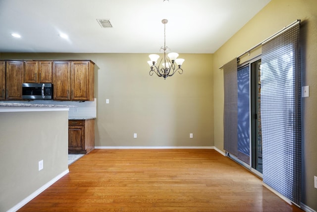 kitchen featuring decorative light fixtures, light hardwood / wood-style floors, tasteful backsplash, and a notable chandelier