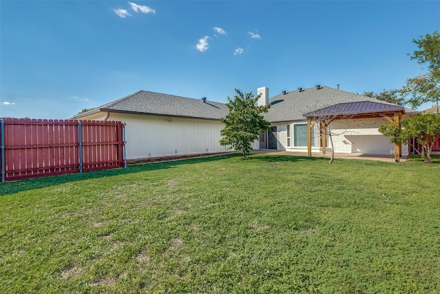 rear view of property featuring a patio area, fence, a lawn, and a gazebo