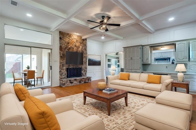 living area with visible vents, coffered ceiling, wood finished floors, beamed ceiling, and a fireplace