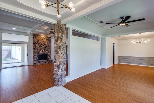 unfurnished living room featuring light hardwood / wood-style floors, ceiling fan with notable chandelier, crown molding, and a fireplace