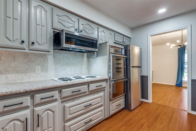 kitchen featuring decorative backsplash, light hardwood / wood-style floors, stainless steel appliances, and a chandelier