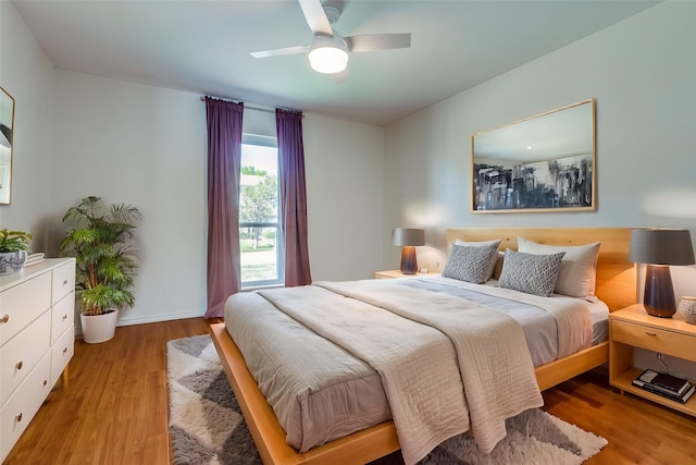 bedroom with a ceiling fan, light wood-style flooring, and baseboards