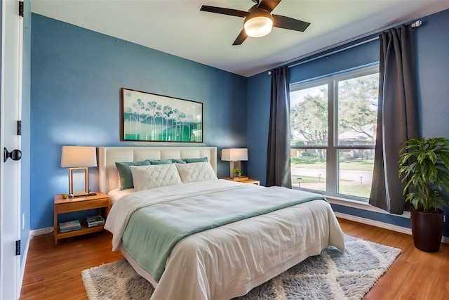 bedroom with ceiling fan, wood finished floors, and baseboards