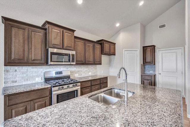 kitchen featuring decorative backsplash, sink, appliances with stainless steel finishes, and light stone countertops