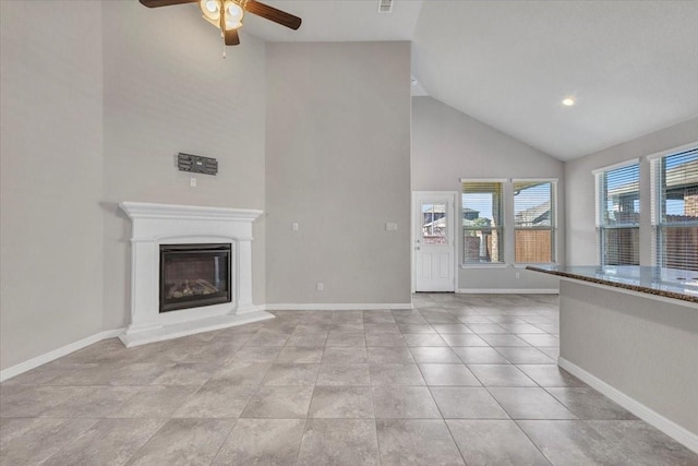 unfurnished living room with ceiling fan, high vaulted ceiling, and light tile patterned flooring