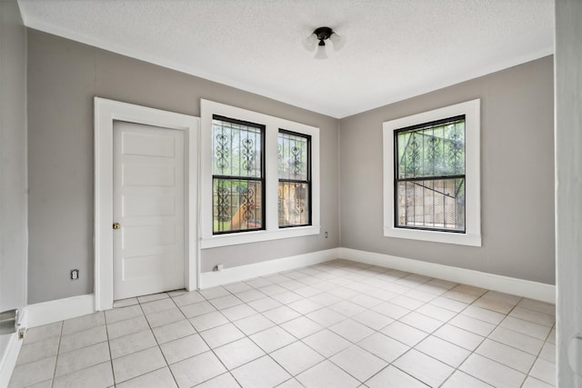 tiled empty room featuring a healthy amount of sunlight and a textured ceiling