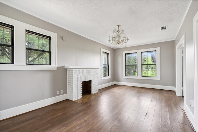 unfurnished living room with dark wood-type flooring, a healthy amount of sunlight, a fireplace, and an inviting chandelier