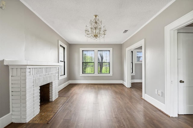 unfurnished living room with dark hardwood / wood-style floors, a notable chandelier, a fireplace, a textured ceiling, and crown molding