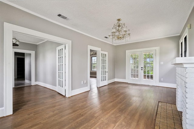 unfurnished dining area with french doors, plenty of natural light, dark hardwood / wood-style floors, ornamental molding, and a notable chandelier