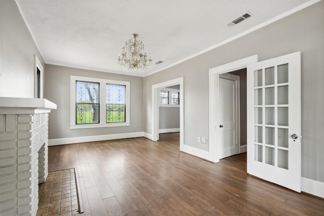 unfurnished living room with a textured ceiling, a fireplace, a chandelier, and dark hardwood / wood-style floors