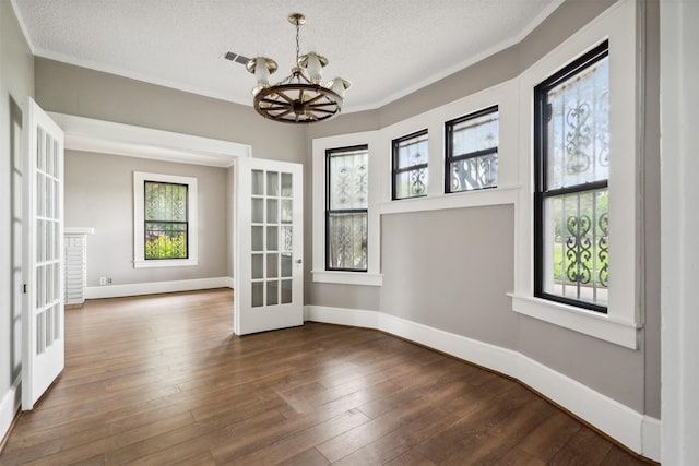 unfurnished room with a healthy amount of sunlight, french doors, dark hardwood / wood-style flooring, and a chandelier