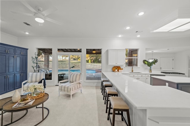 kitchen with a breakfast bar area, white cabinets, a center island, ceiling fan, and blue cabinetry